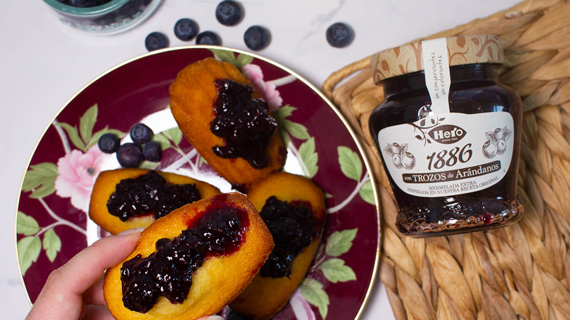 hand holding a cake with jam on it